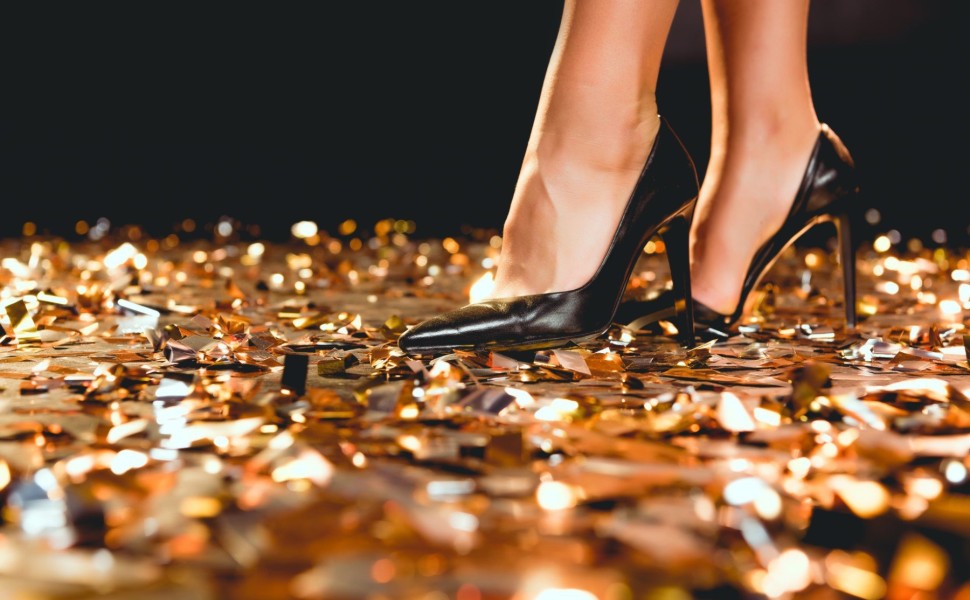 cropped view of girl in black high heel shoes standing on golden confetti