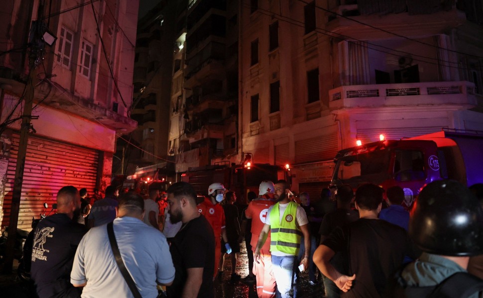 People stand near a damaged building at the site of an Israeli air strike, in Beirut, Louisa Gouliamaki/Reuters